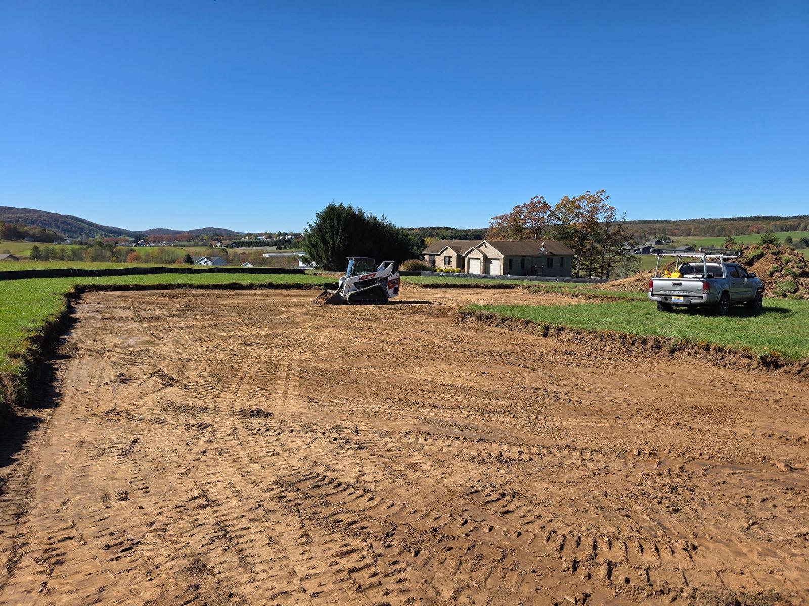 A graded building pad at Green Meadow, with clean track lines.