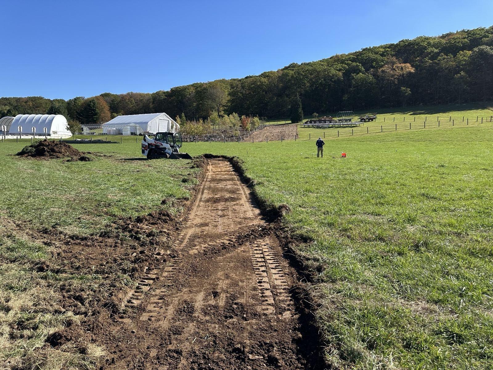 A long open utility trench running toward the site at Green Meadow.