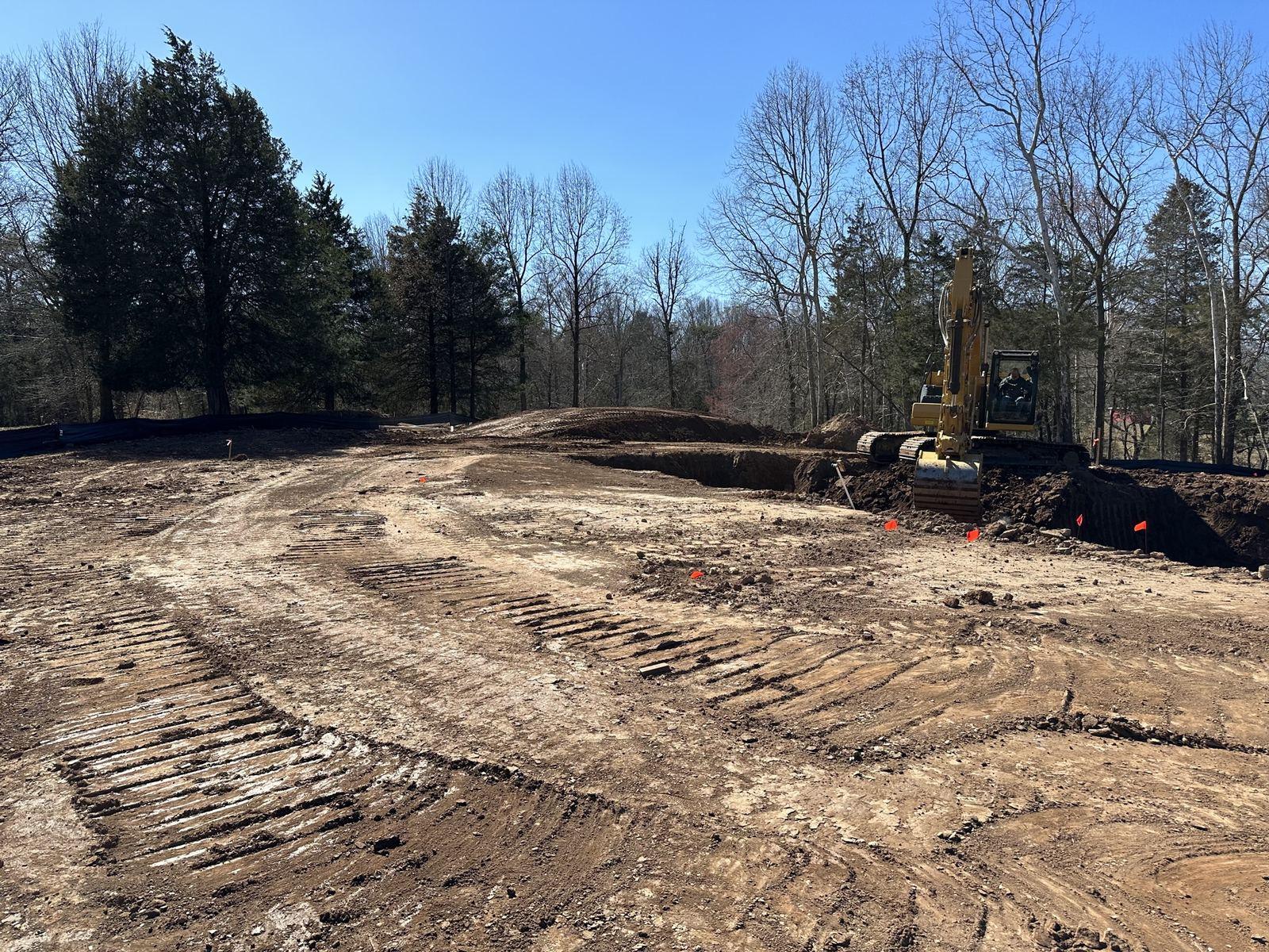 Freshly cleared ground at Haymarket, with an excavator at the tree line.