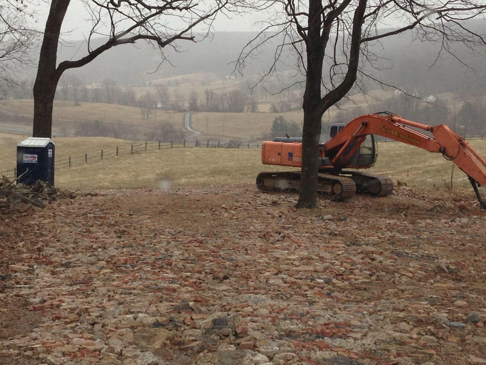 The lot cleared, with an excavator finishing the grade.